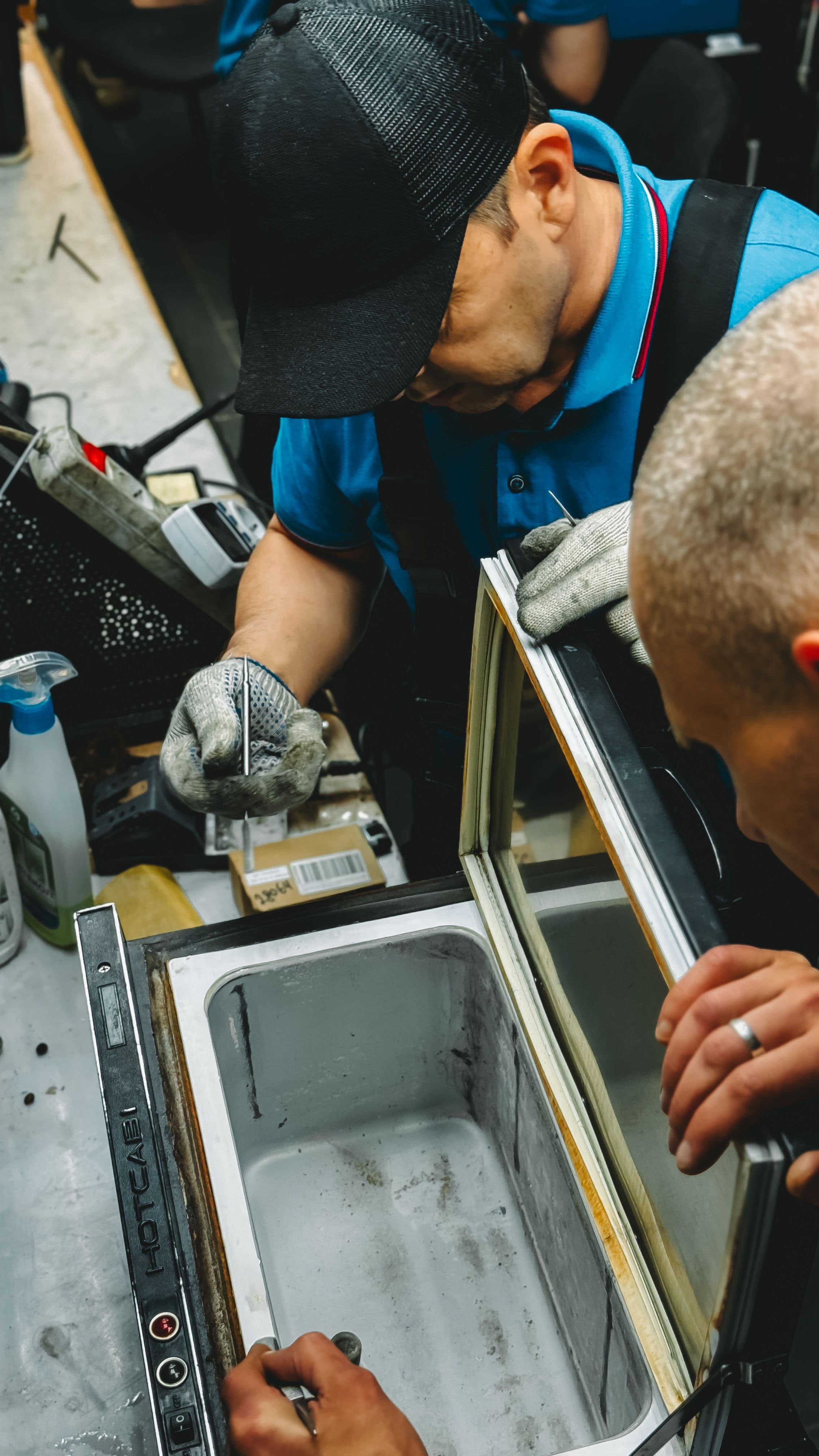 Two technicians repairing a commercial freezer unit